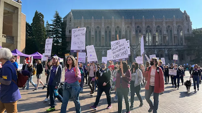 Image of UW workers protesting for fair pay. Many are wearing purple and holding signs.